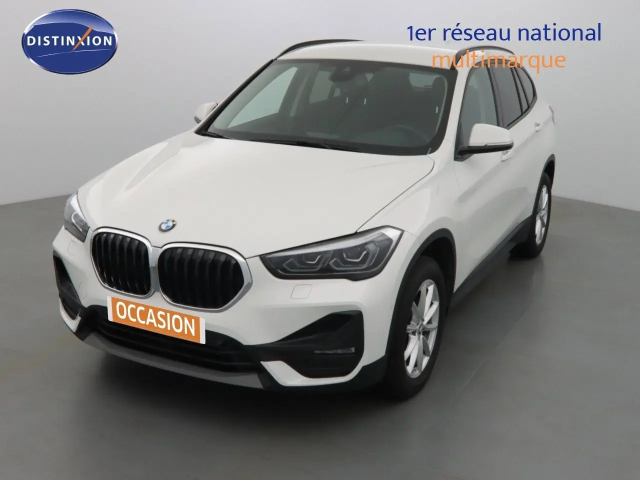 BMW X1 blanc Alpine metal vue 3/4 avant droit avec calandre noire et jantes argentées en intérieur studio