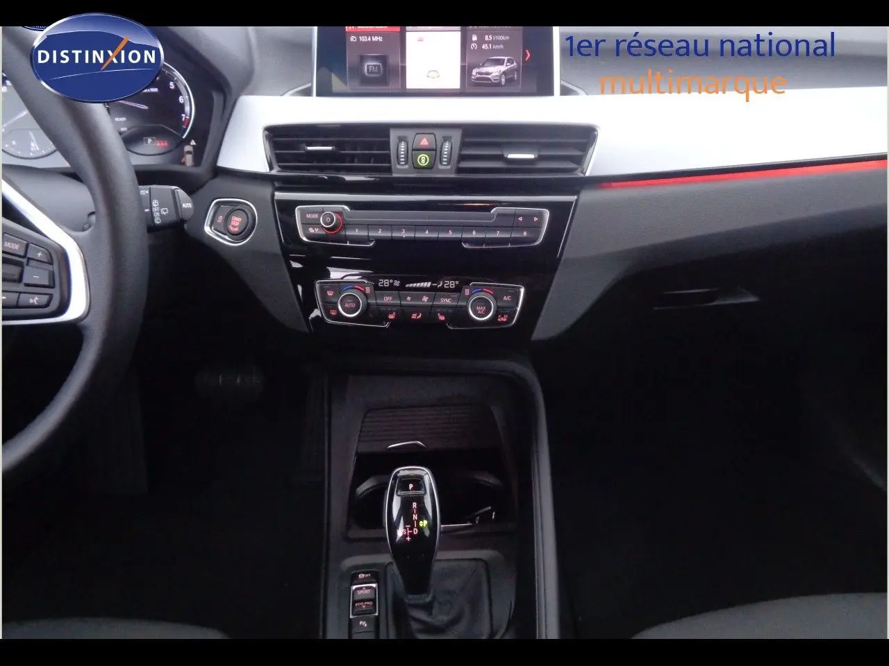 Intérieur noir du BMW X1 2022, vue centrée sur la console centrale avec levier de vitesse automatique et tableau de bord digital.