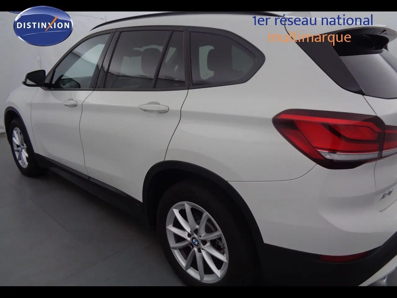 BMW X1 blanc Alpine métal vu de profil côté gauche, mettant en valeur les feux arrière et les jantes alliage.