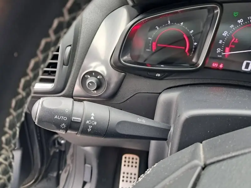 Gros plan sur la commande des phares et le tableau de bord numérique rouge d'une Citroën DS5 gris foncé 2014.