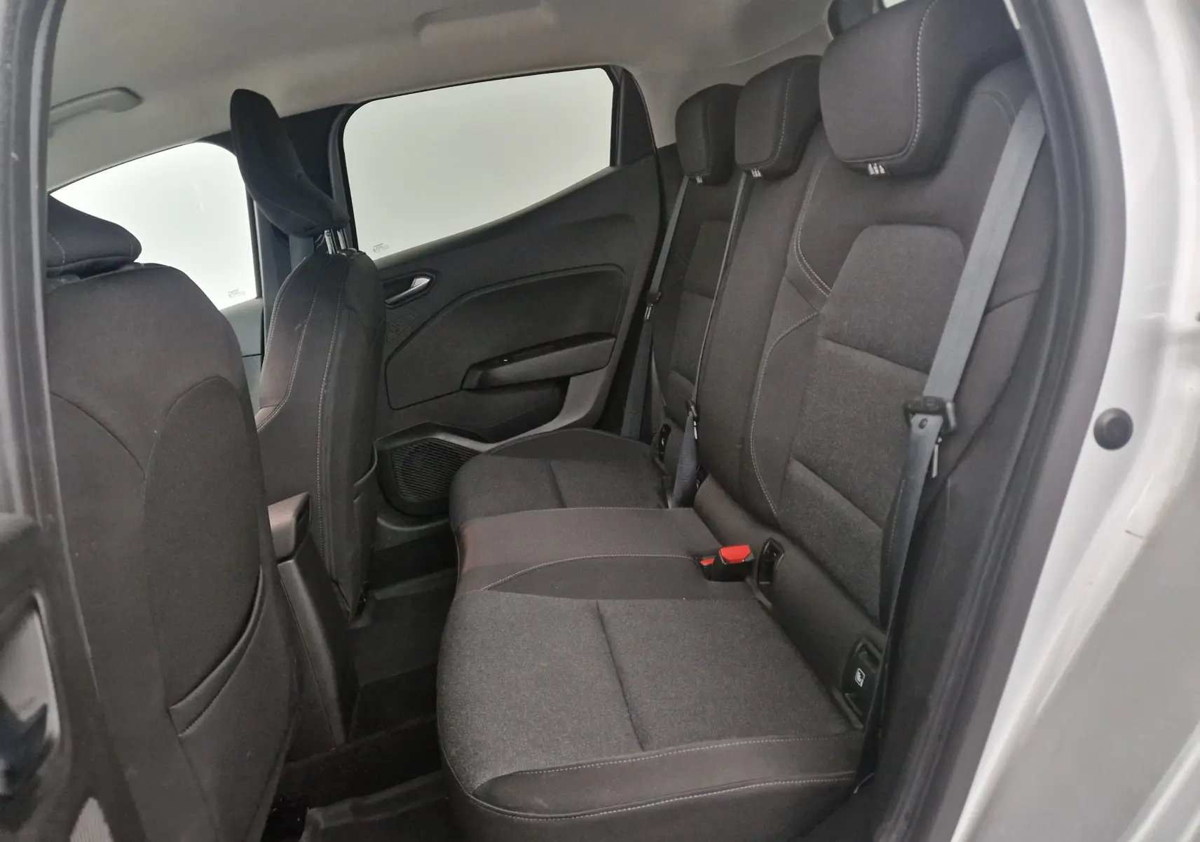 Vue intérieure arrière côté droit de la Renault Clio V gris platine, montrant les sièges arrière en tissu noir et gris.