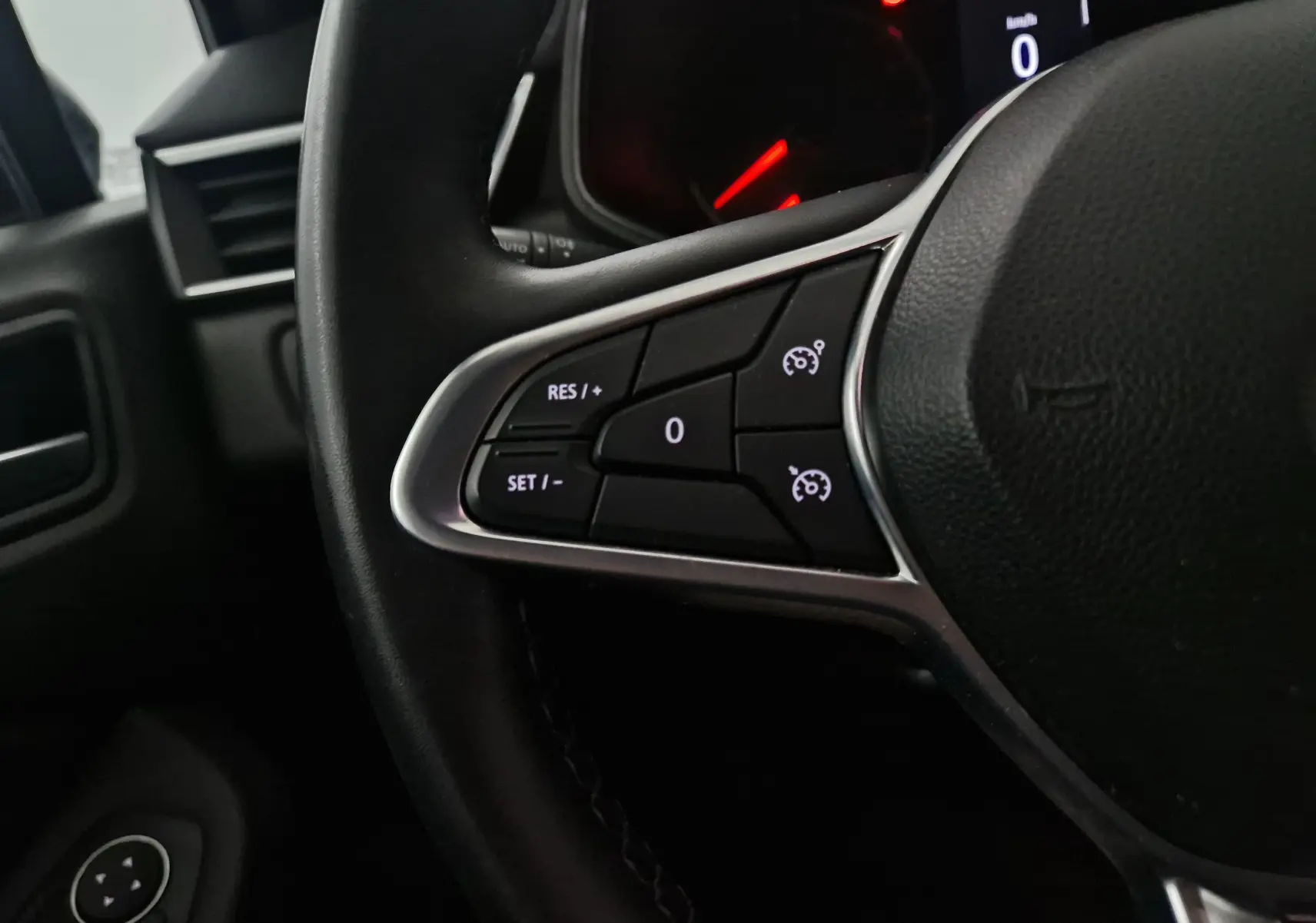 Gros plan sur les commandes de régulateur de vitesse au volant d'une Renault Clio V 1.0 TCE 90 Zen, intérieur noir.