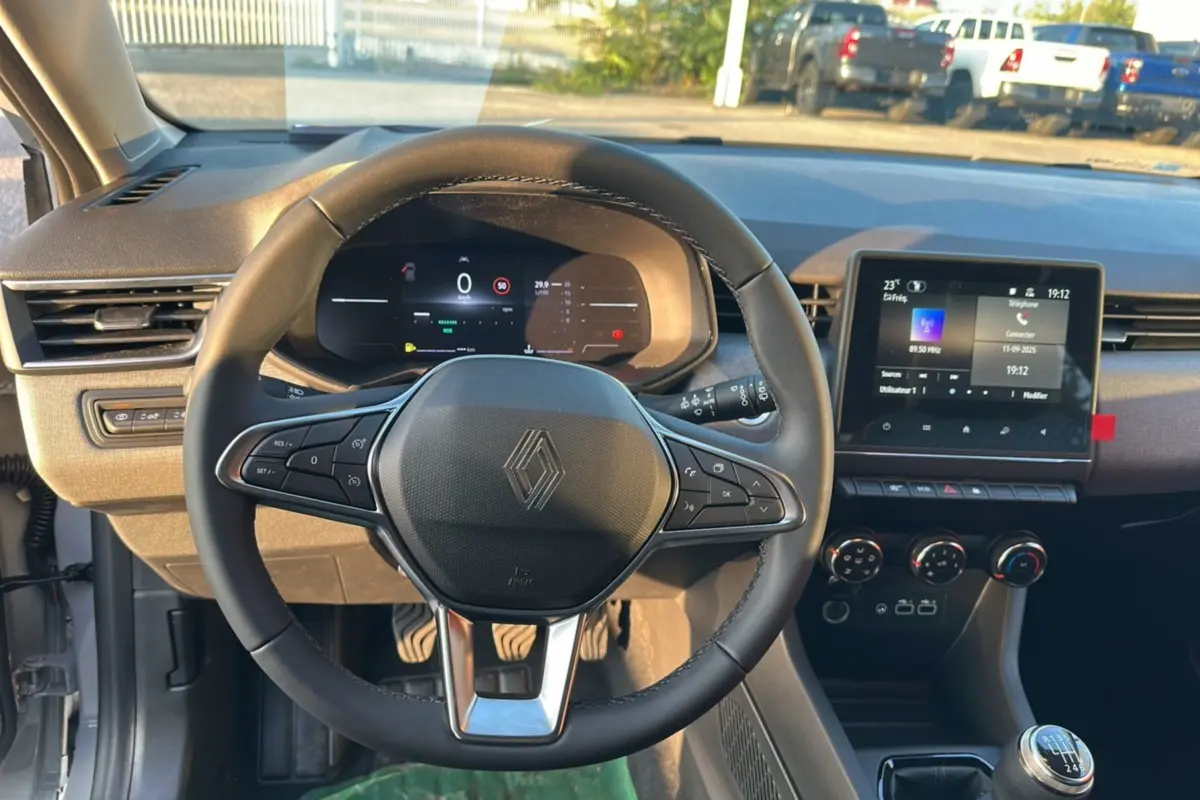 Vue intérieure centrée sur le volant de la Renault Clio DCI 100 Evolution Camera 2025 en gris rafale, avec tableau de bord numérique et écran tactile.