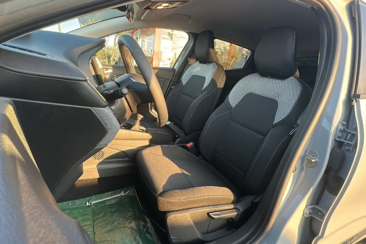 Vue intérieure côté conducteur de la Renault Clio DCI 100 Evolution Camera 2025 en gris rafale, sièges tissu noir et gris.