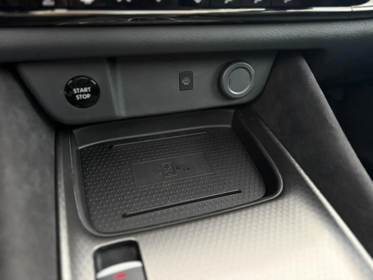 Gros plan sur la console centrale du Nissan Qashqai 2025, montrant le chargeur à induction et le bouton start/stop.