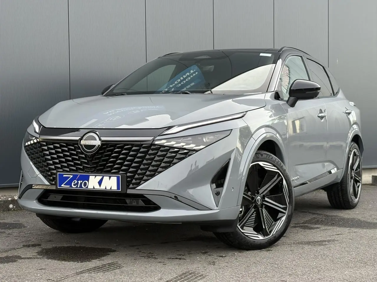 Nissan Qashqai 2025 gris Ceramic en 3/4 avant droit avec toit noir panoramique et jantes alliage 20 pouces.