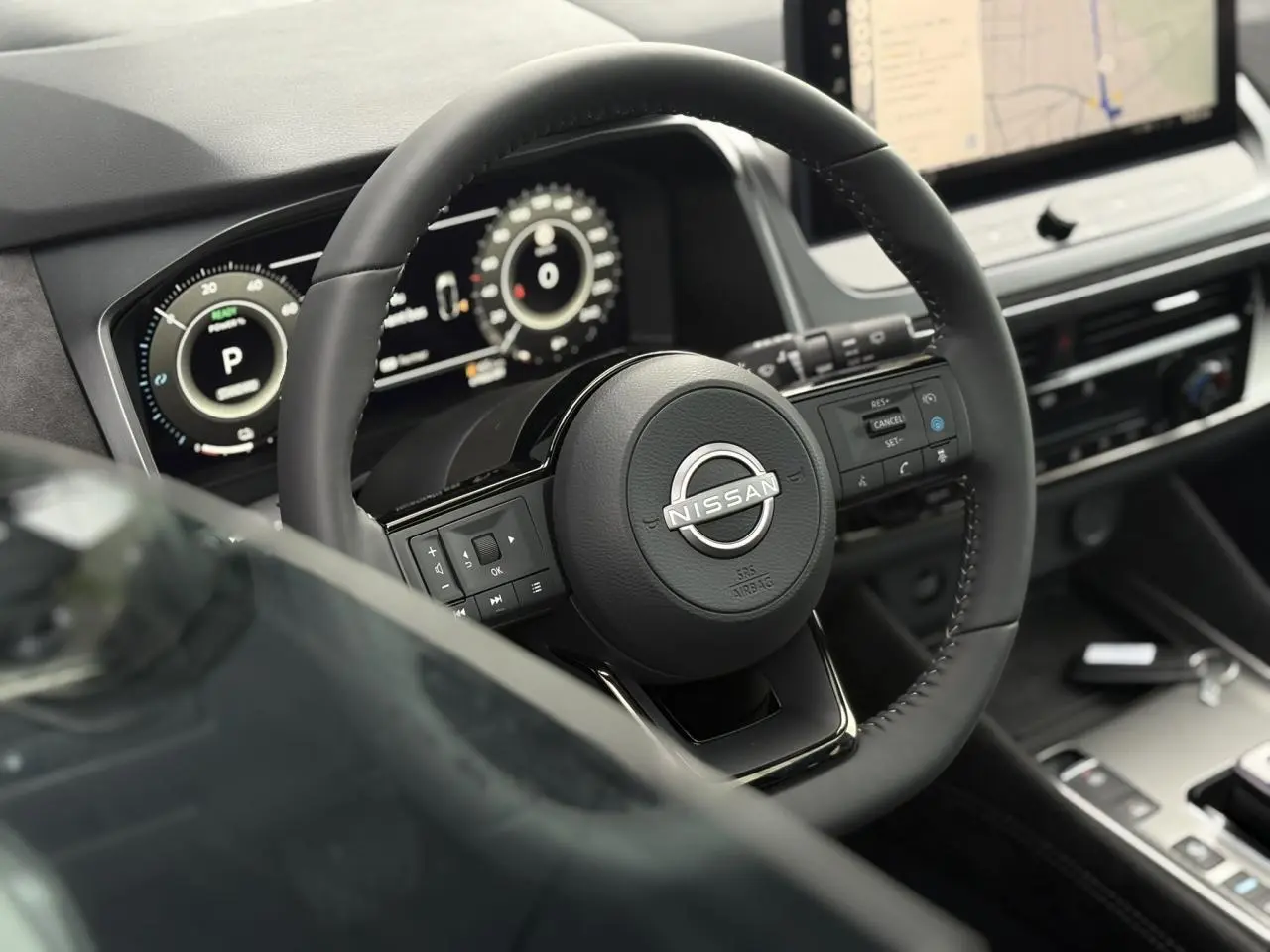 Vue rapprochée du volant cuir noir du Nissan Qashqai 2025 avec tableau de bord numérique et écran tactile central.