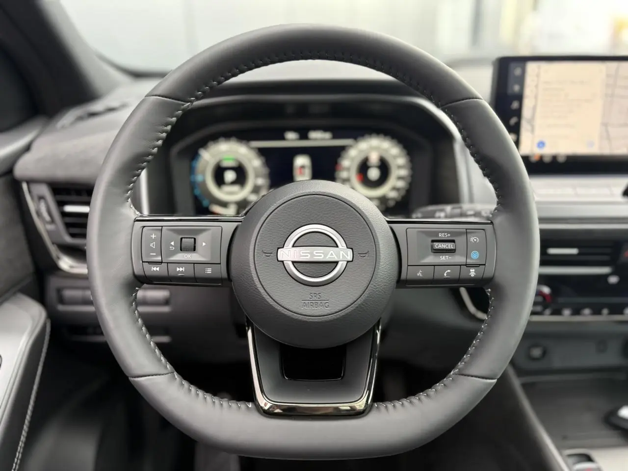 Volant cuir noir de Nissan Qashqai 2025 avec commandes intégrées, tableau de bord numérique et écran tactile GPS visible.