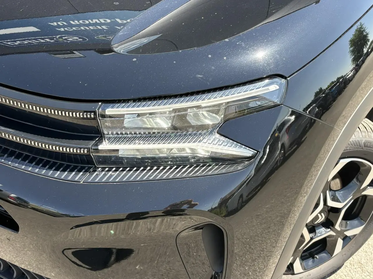Gros plan sur le phare avant droit noir Perla du Citroën C5 Aircross Hybrid 2025 avec jante alliage bicolore.