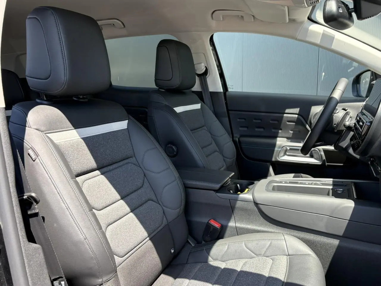 Vue intérieure côté droit des sièges avant en tissu et cuir noir du Citroën C5 Aircross Hybrid 2025 avec accoudoir central.