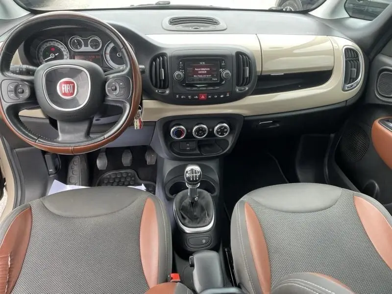 Intérieur beige et marron de la Fiat 500L 1.6 Multijet 2014, vue frontale du tableau de bord avec volant et boîte manuelle.