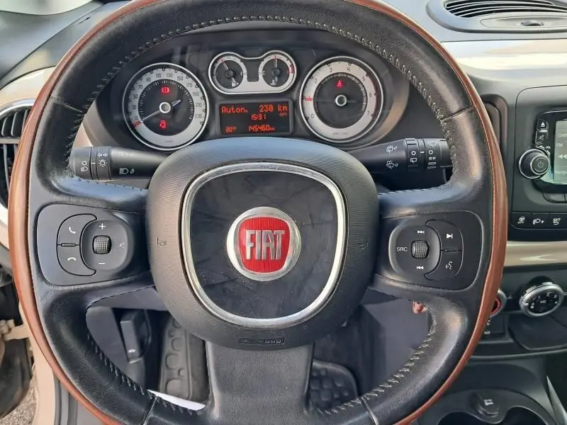 Vue rapprochée du volant noir du Fiat 500L beige 2014, affichant le tableau de bord et les commandes intégrées.
