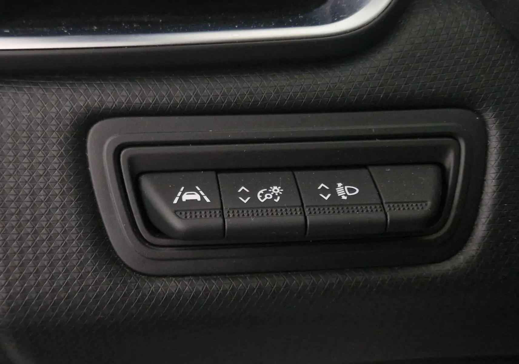 Boutons de réglage d'assistance à la conduite et éclairage sur tableau de bord noir d'une Renault Clio V gris platine.