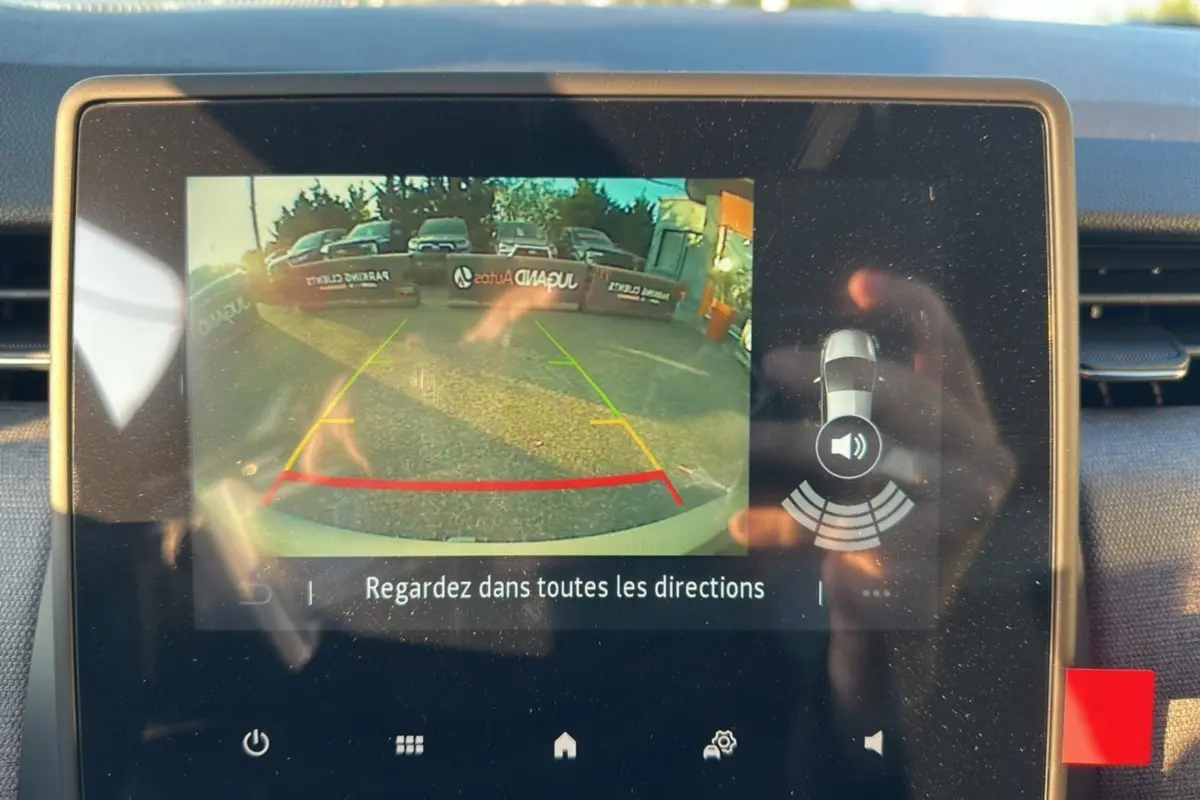 Écran de caméra de recul de la Renault Clio DCI 100 Evolution Gris Rafale montrant l'arrière avec lignes de guidage colorées.