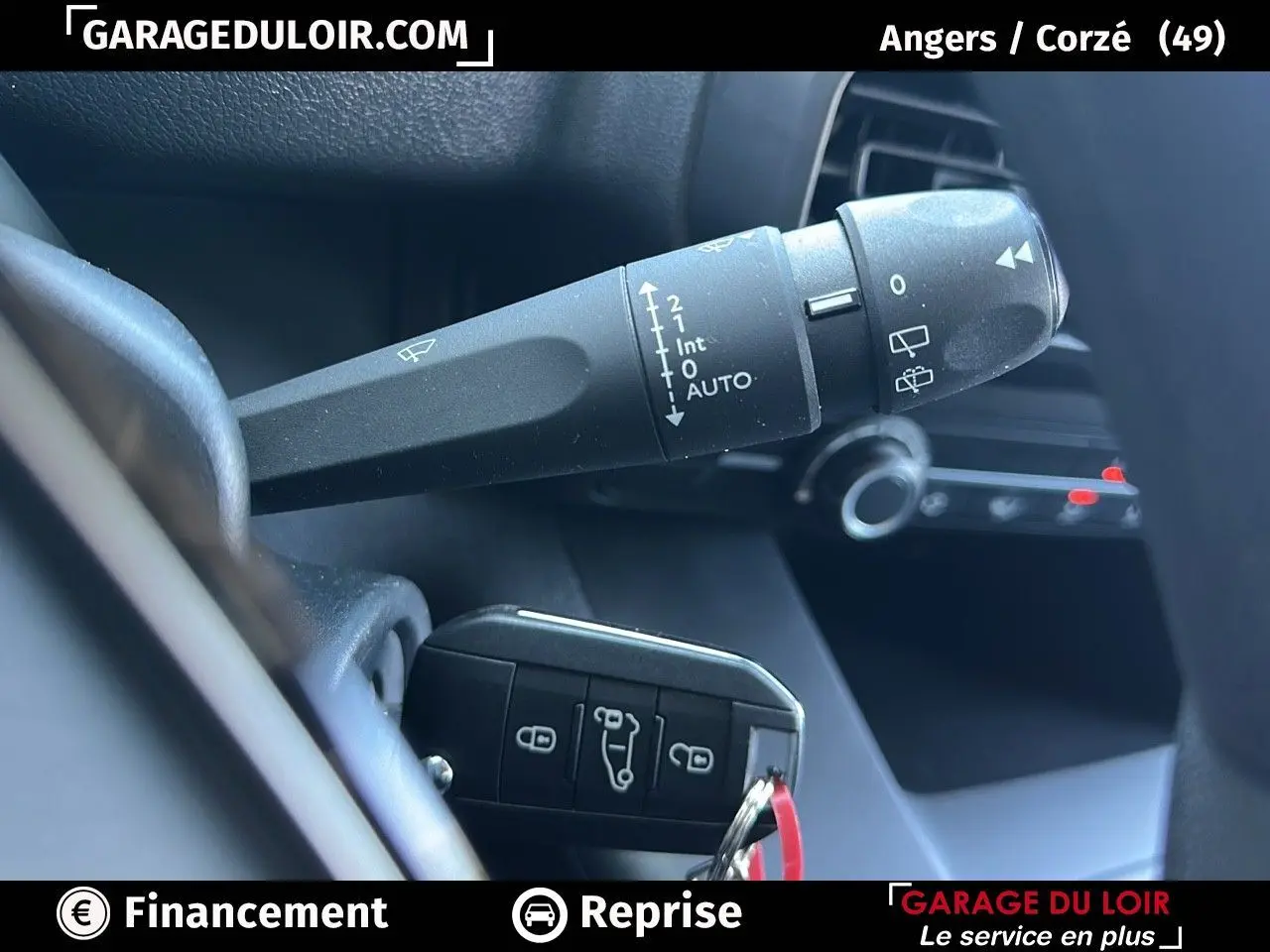 Gros plan sur la commande d'essuie-glace et la clé de contact dans l'habitacle d'un Peugeot Rifter bleu 2024.