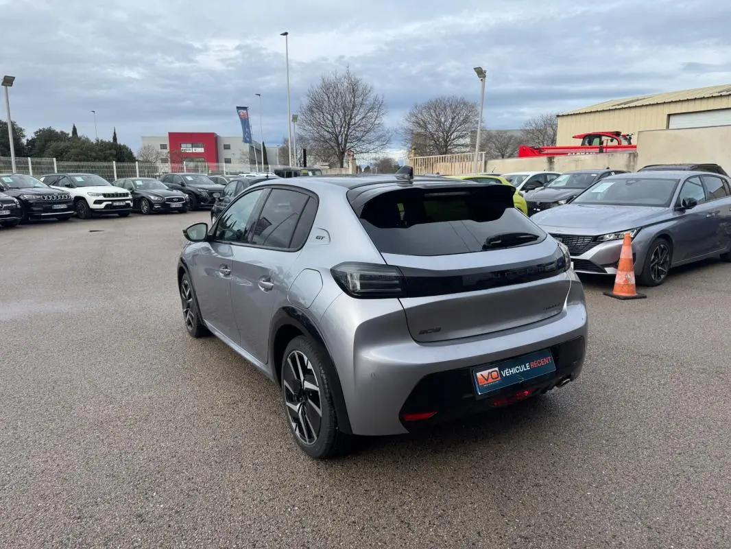 Vue 3/4 arrière droite d'une Peugeot 208 Hybrid 110 gris métallisé avec jantes alliage 17 pouces et vitres teintées.