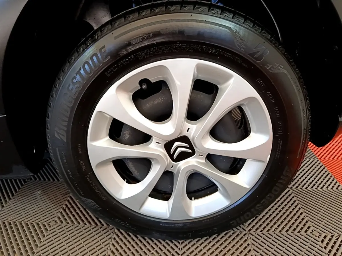 Gros plan sur la jante argentée avec logo Citroën au centre, pneu Bridgestone monté sur Citroën C3 blanche.