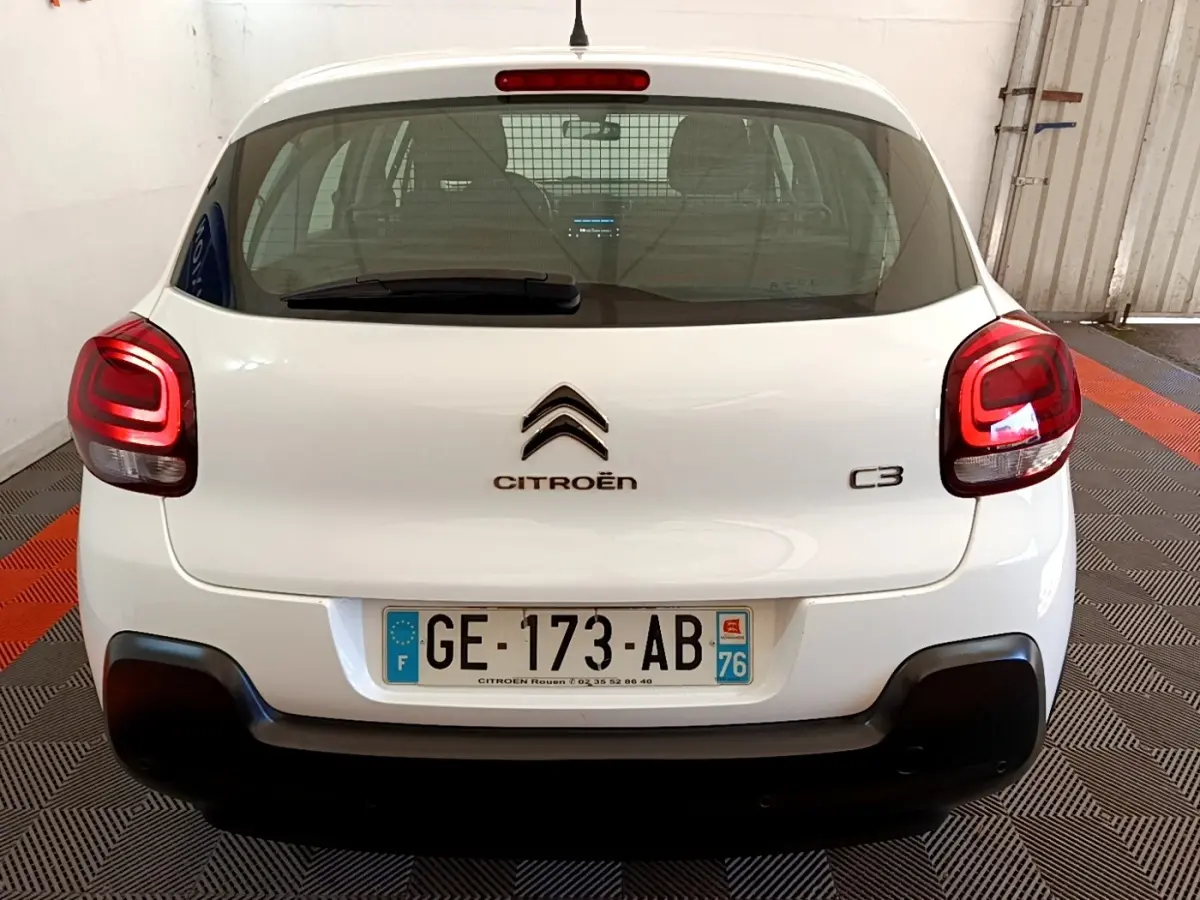 Vue arrière d'une Citroën C3 blanche 2022 avec feux arrière LED et pare-chocs noir dans un garage.