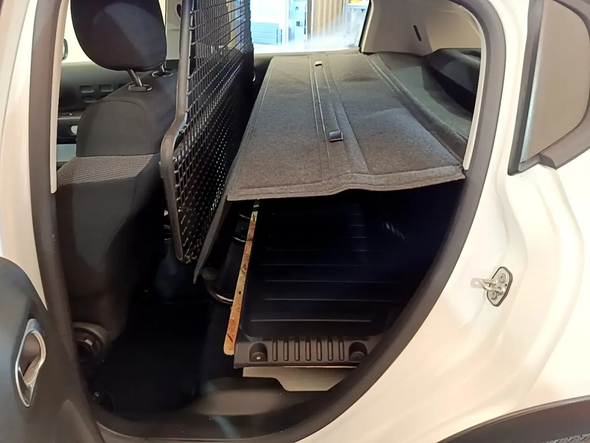 Vue intérieure côté droit du coffre blanc Citroën C3 2022 avec séparation grillagée et plancher modulable.