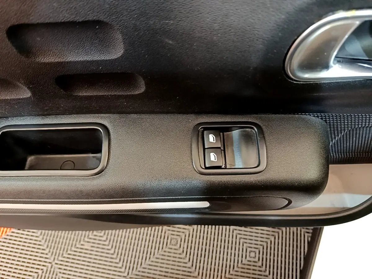Gros plan sur la commande des vitres électriques côté conducteur de la porte intérieure noire d'une Citroën C3.