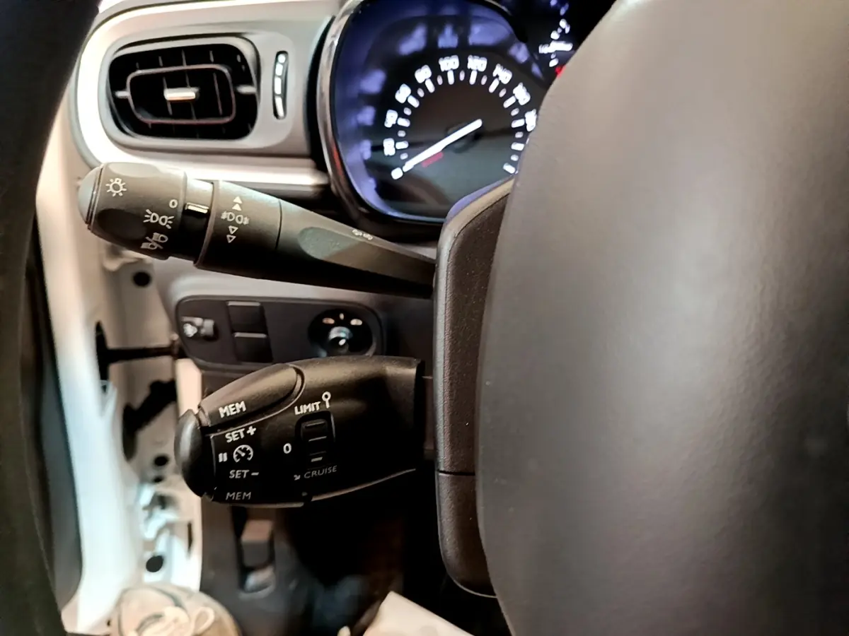 Gros plan sur les commandes au volant et le tableau de bord éclairé d’une Citroën C3 blanche, version Feel 2022.