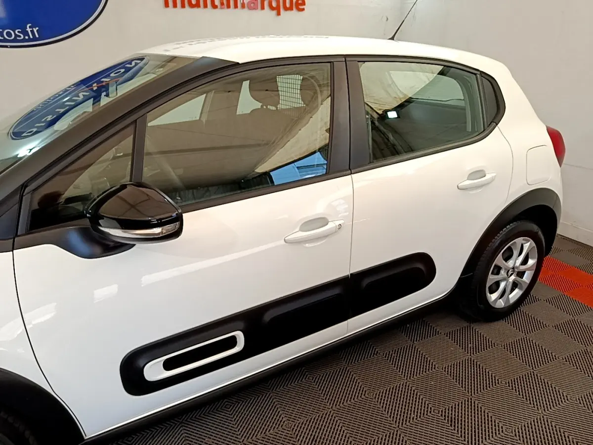 Vue latérale droite d'une Citroën C3 blanche 2022 avec protections noires caractéristiques sur les portières.