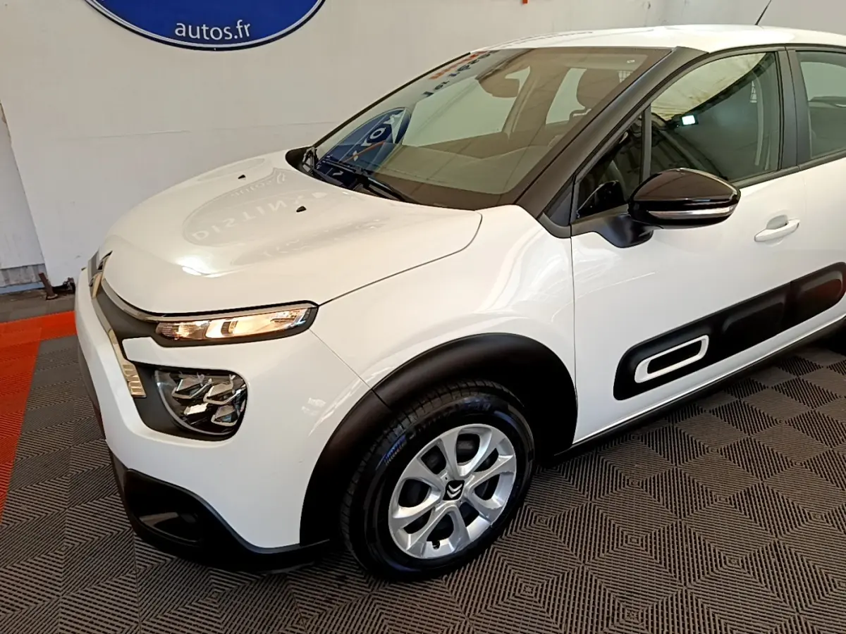 Vue 3/4 avant droite d'une Citroën C3 blanche avec protections latérales noires et jantes argentées.