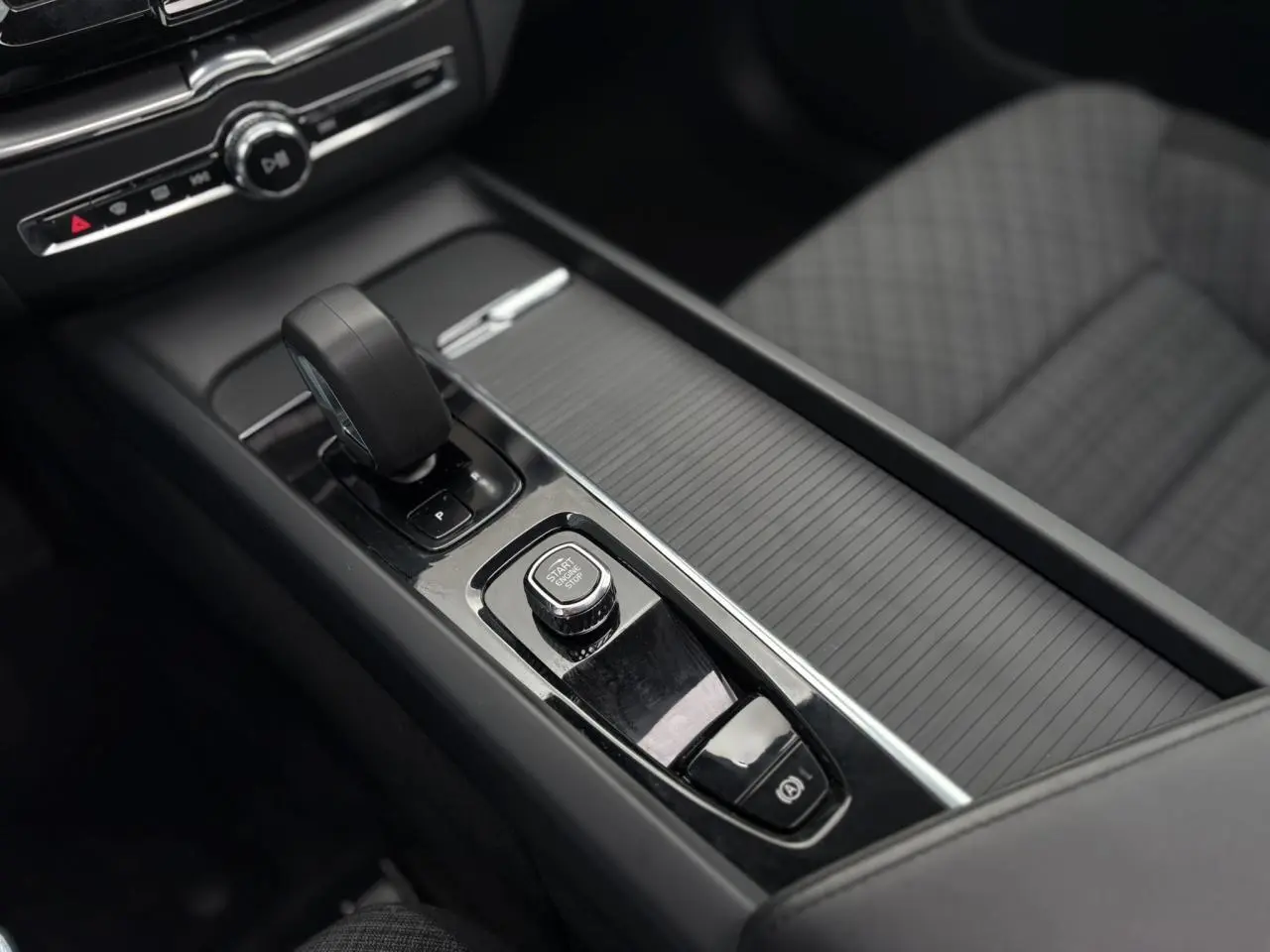 Vue rapprochée de la console centrale noire avec levier de vitesses et bouton start/stop du Volvo XC60 2024.