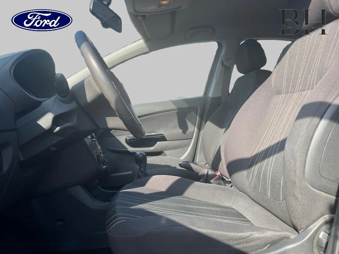 Vue intérieure côté conducteur de l'Opel Corsa noir 2010, montrant siège, volant et levier de vitesse manuel.