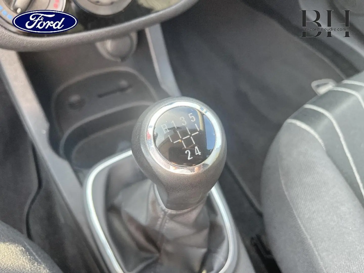 Gros plan sur le levier de vitesses manuel d'une Opel Corsa noire de 2010, montrant les rapports gravés.