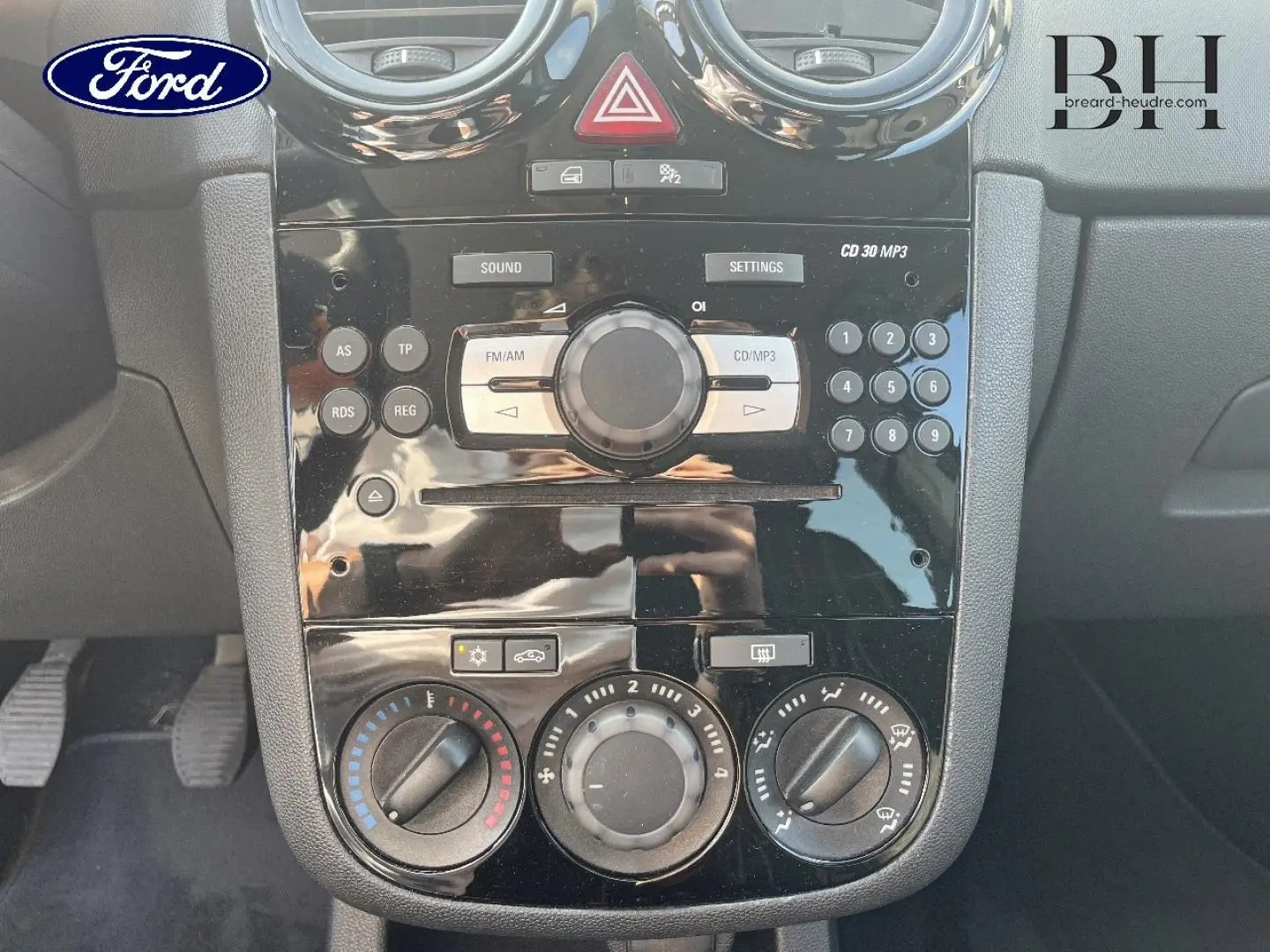Console centrale noire de l’Opel Corsa 1.2 Twinport GPL Essentia 2010 avec commandes radio et climatisation manuelle.