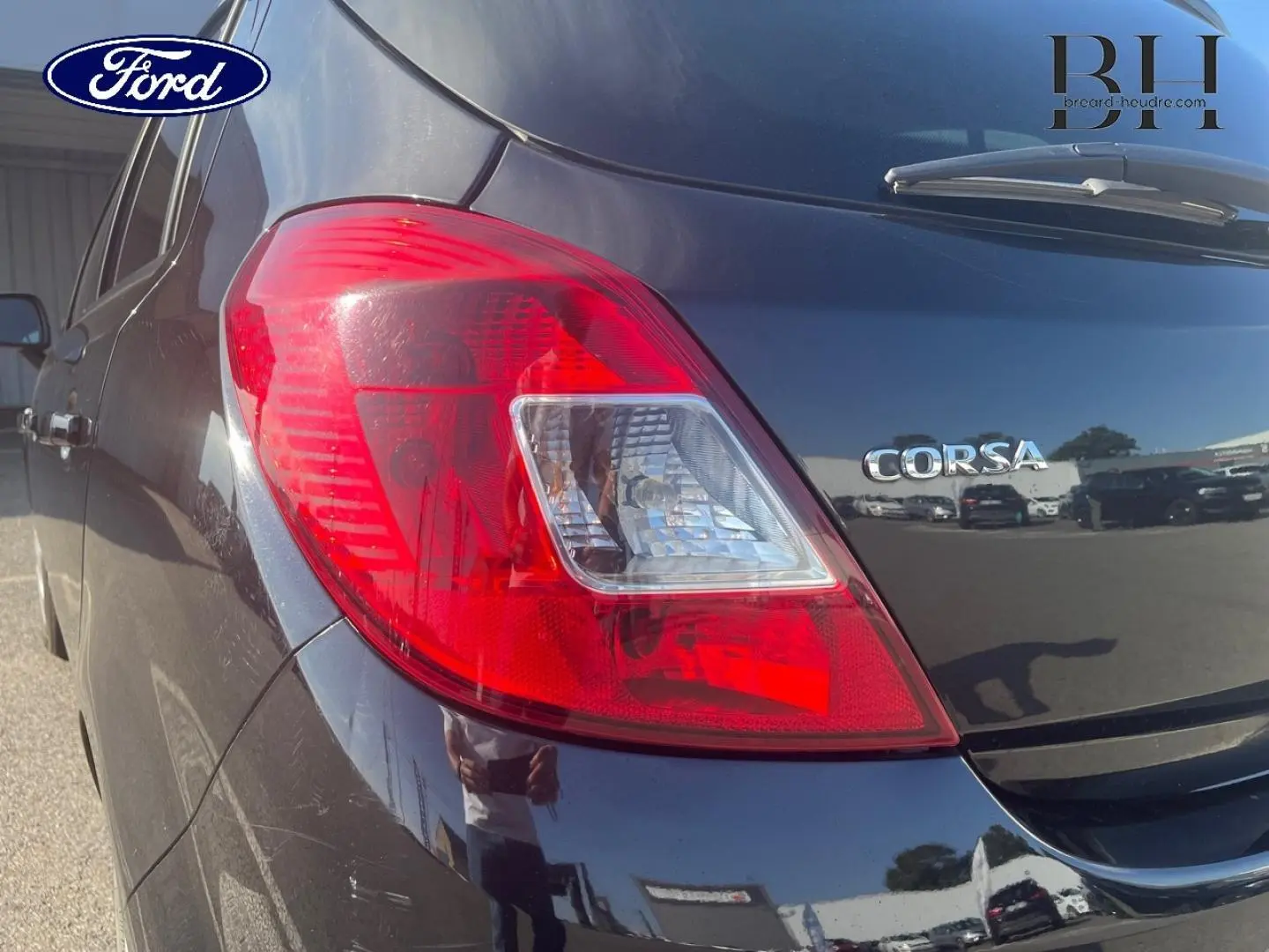 Gros plan sur le feu arrière droit d’une Opel Corsa noire de 2010, avec le logo Corsa visible sur le hayon.