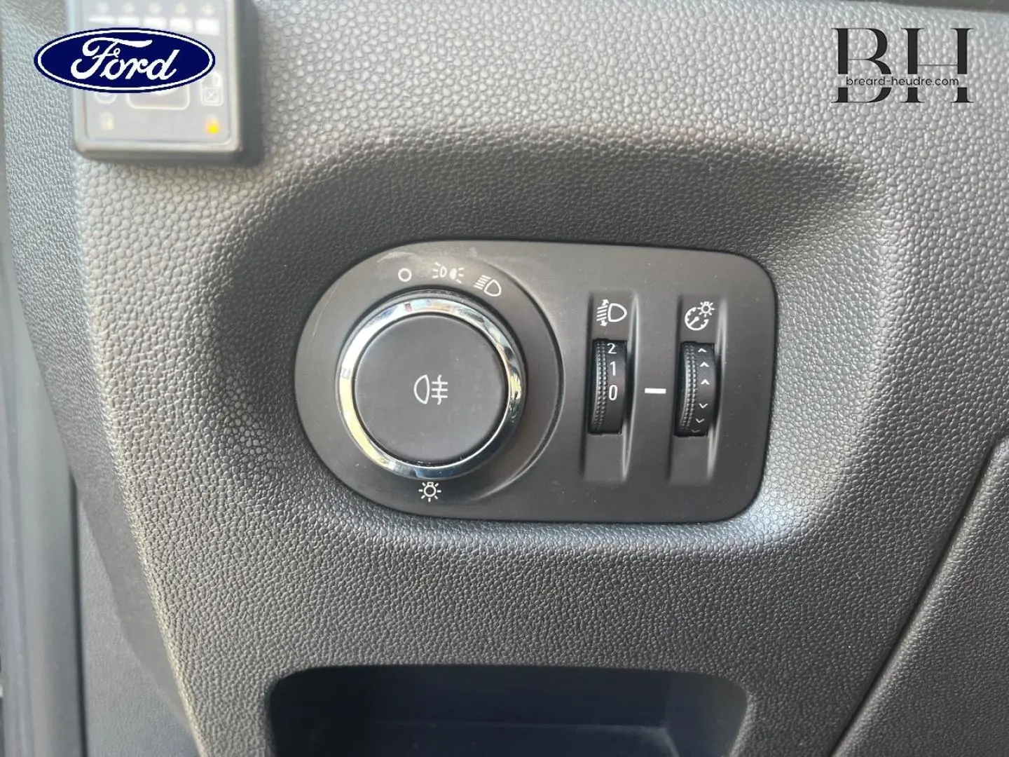 Gros plan sur les commandes d’éclairage intérieures d’une Opel Corsa noire, bouton rotatif et réglages lumineux visibles.