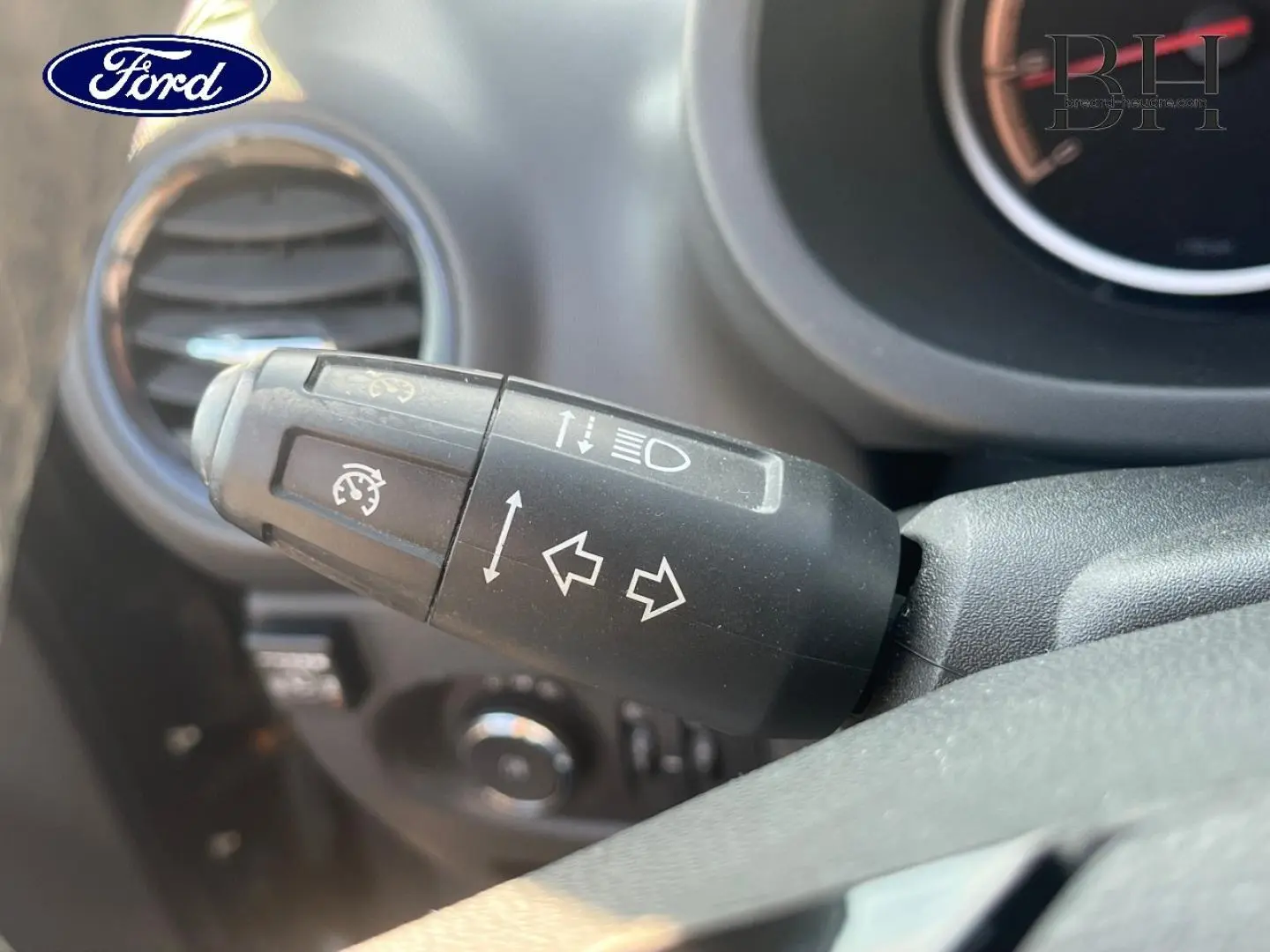 Gros plan sur la commande de clignotants et feux d’une Opel Corsa noire, vue côté conducteur intérieur.