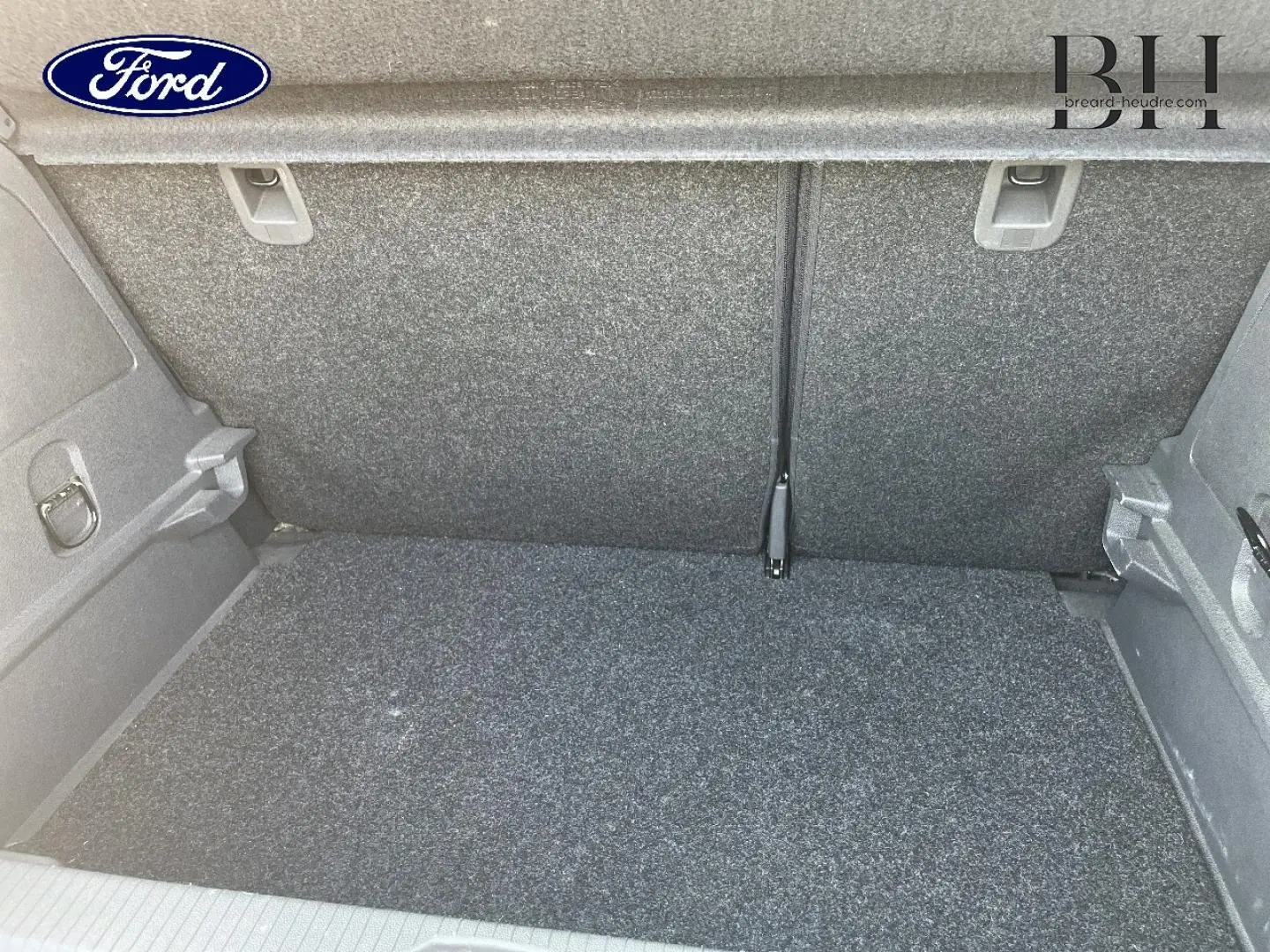 Coffre vide de l’Opel Corsa 1.2 Twinport GPL noir, vue intérieure arrière avec revêtement gris.