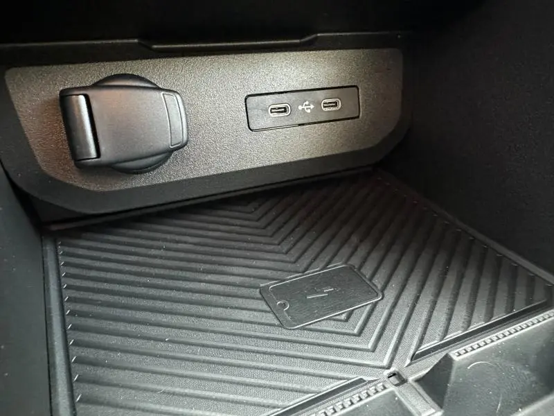 Gros plan sur la console centrale du Dacia Duster 2025, montrant deux ports USB-C et un espace de recharge sans fil noir.