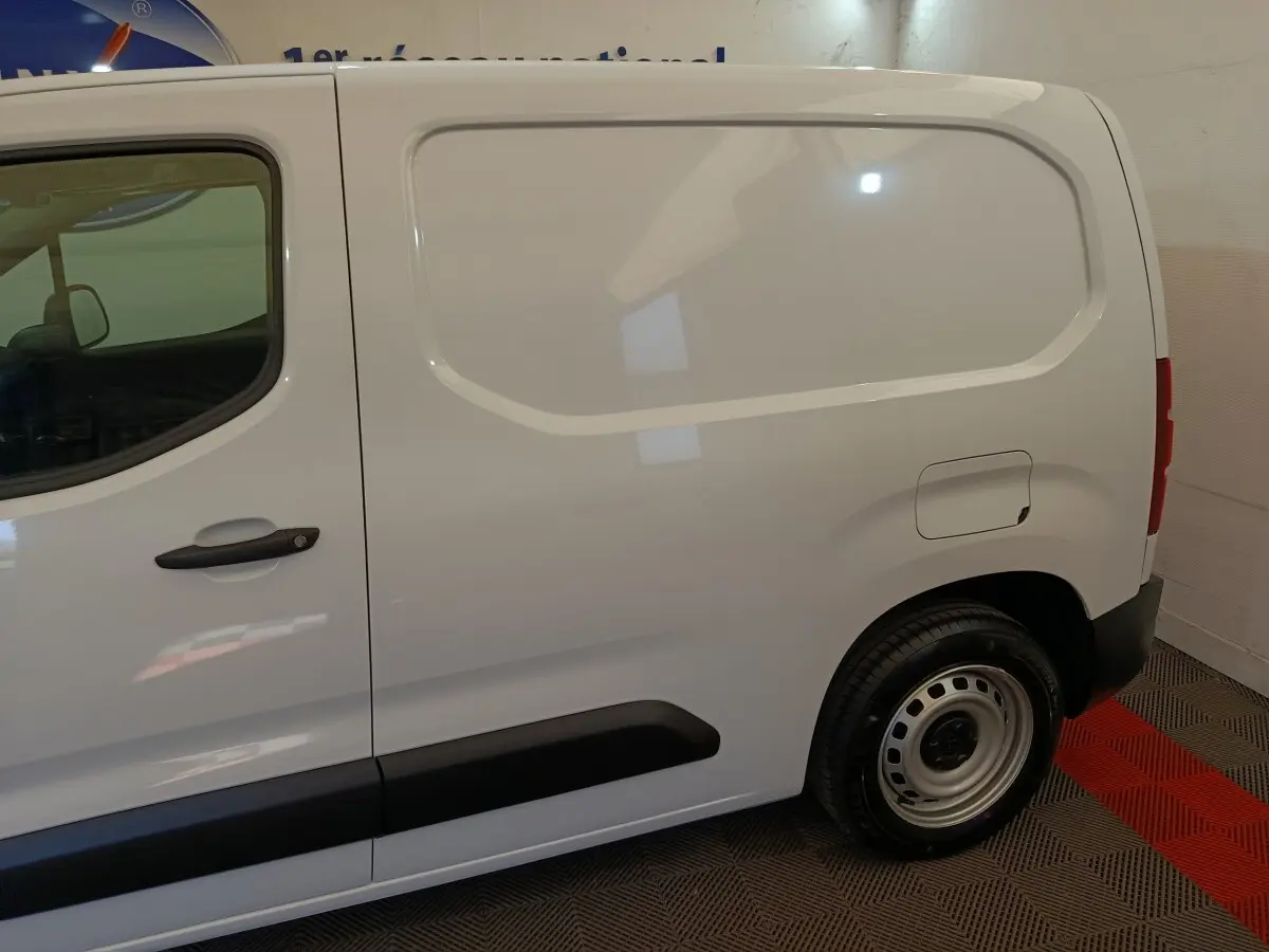 Vue latérale droite d’un utilitaire Peugeot Partner blanc avec porte latérale pleine et jante acier simple.