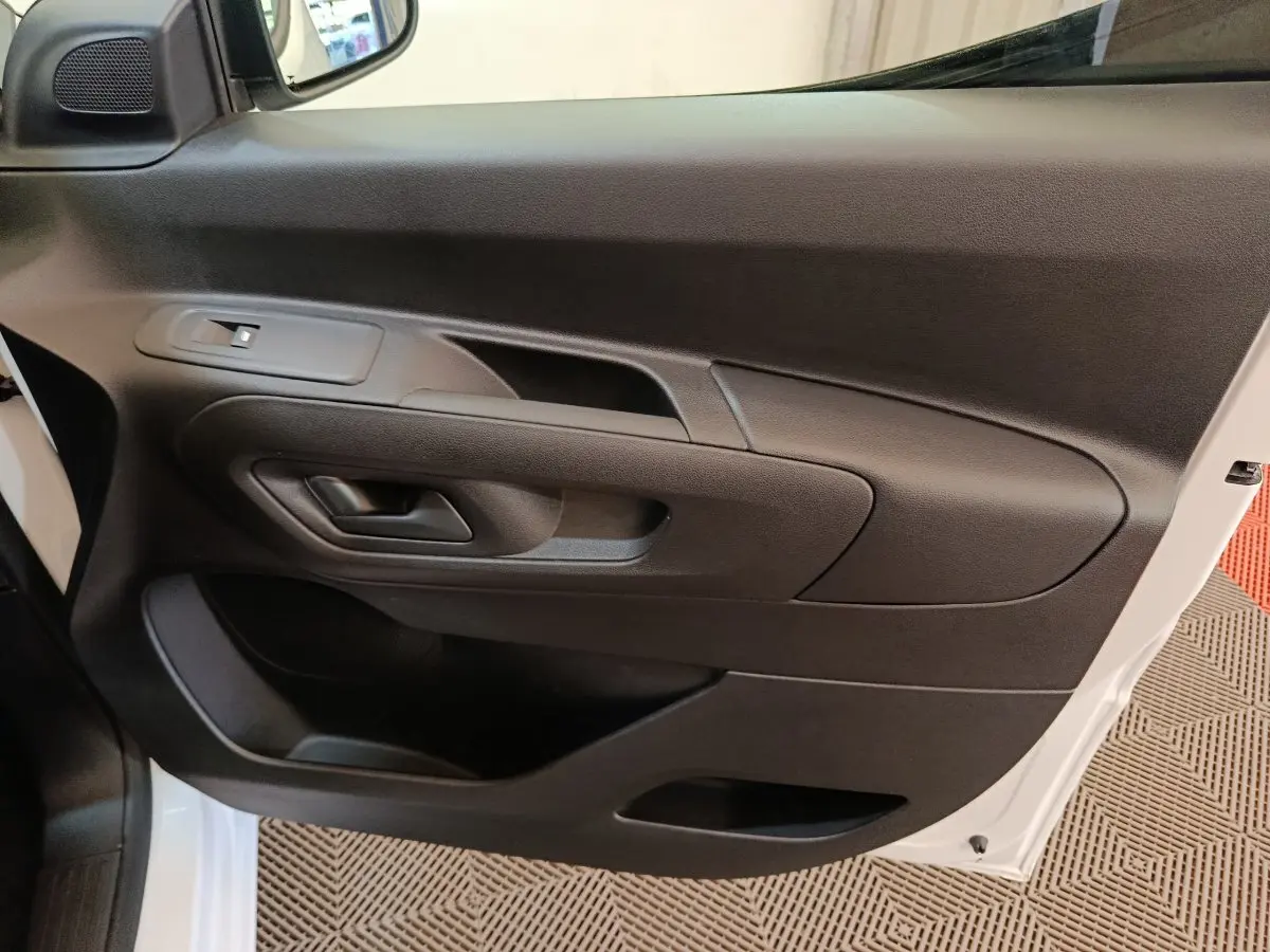Vue intérieure côté conducteur de la porte noire du Peugeot Partner blanc, avec poignée et commande de vitre.