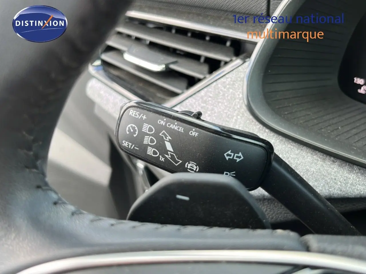Gros plan sur la manette de commandes au volant d'une Skoda Scala gris magnétique, avec tableau de bord gris noir en arrière-plan.