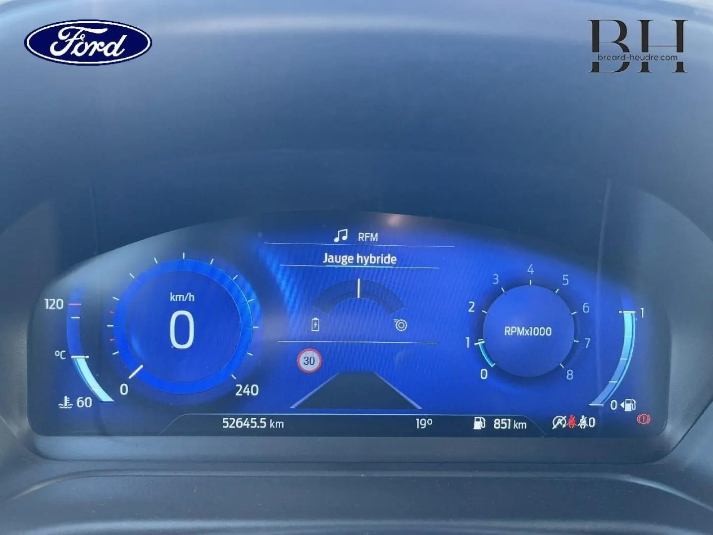 Tableau de bord numérique du Ford Puma 2024, affichage bleu avec jauge hybride et compte-tours à 0 RPM.