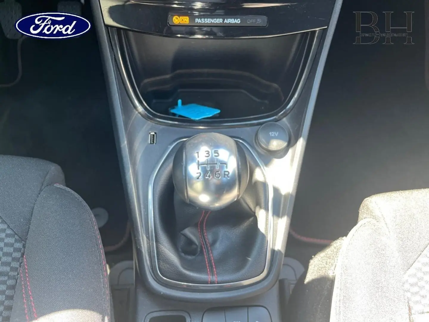 Le levier de vitesses manuel du Ford Puma 2024, avec soufflet noir et surpiqûres rouges, vu de dessus entre les sièges.