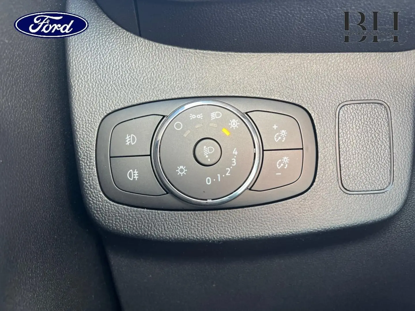 Commande des feux avec réglage d'intensité lumineuse sur tableau de bord noir d'une Ford Puma 2024 gris Solar.