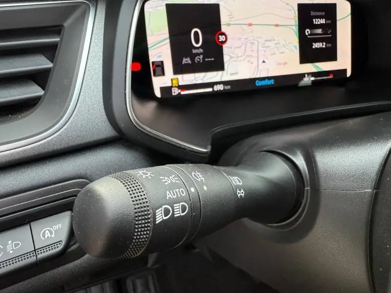 Gros plan sur la commande des feux du Renault Captur 1.0 Eco-G 2025 avec tableau de bord numérique en arrière-plan.