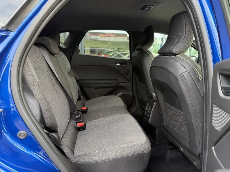Vue intérieure arrière du Renault Captur 2025 Bleu Iron/Noir Etoilé, sièges tissu gris avec appuie-têtes et portières ouvertes.