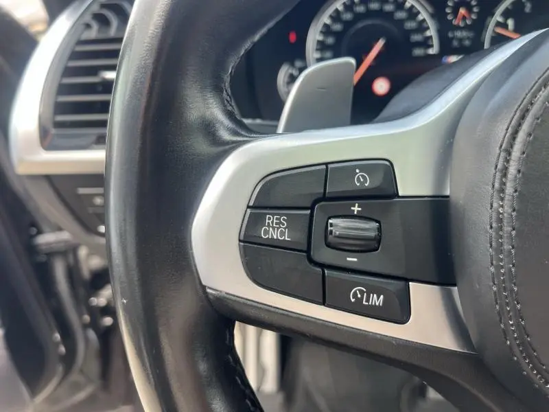 Gros plan sur les commandes de régulateur de vitesse au volant cuir noir du BMW X3 M40iA 2019 Sophistograu métallisé.