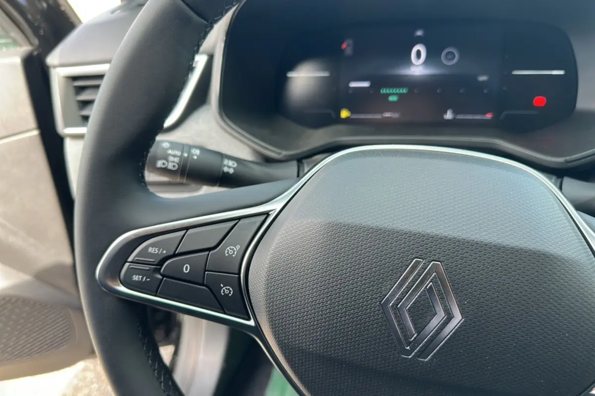 Gros plan sur le volant noir de la Renault Clio DCI 100 Evolution 2025, avec commandes intégrées et tableau de bord numérique.