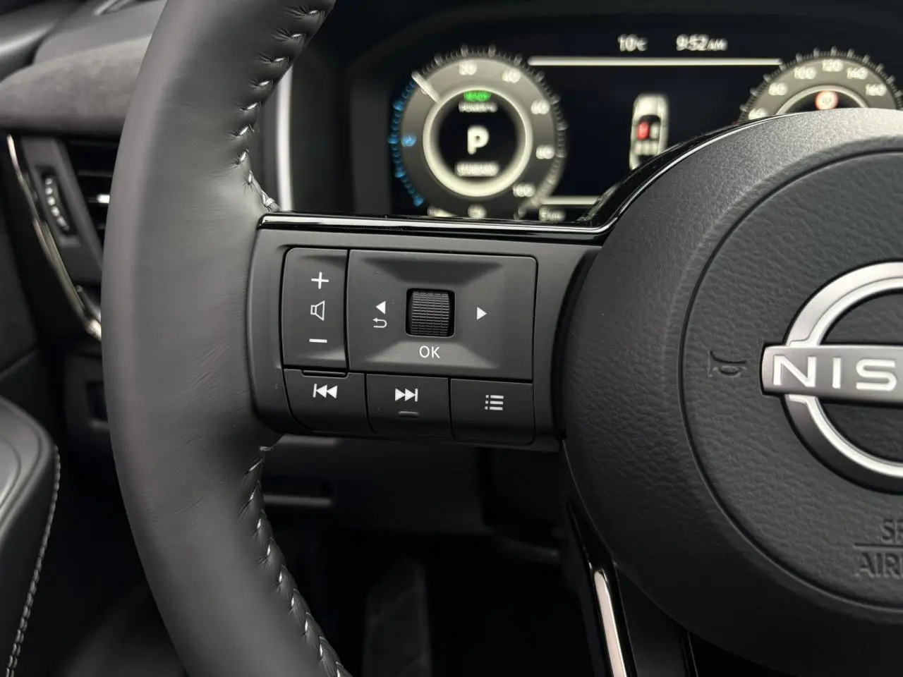 Gros plan sur le volant cuir noir côté gauche du Nissan Qashqai 2025 avec commandes intégrées et tableau de bord numérique.