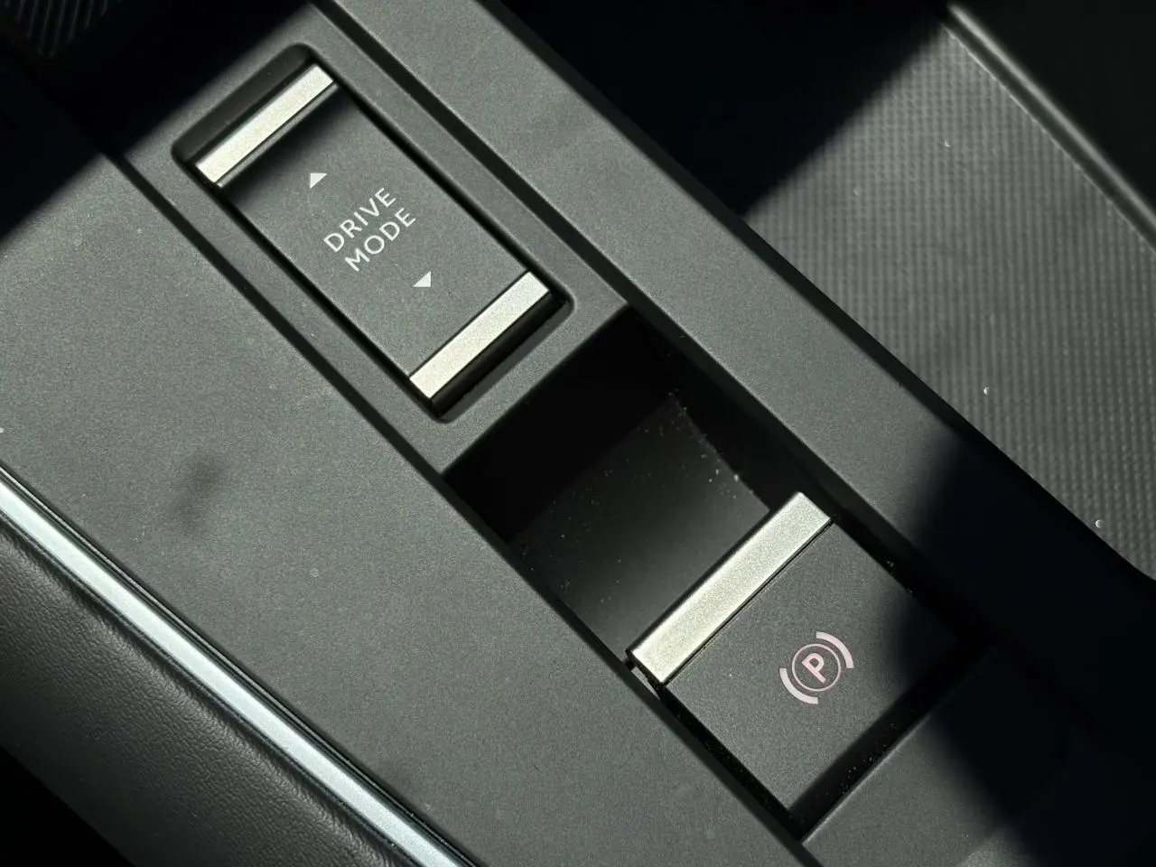 Gros plan sur la console centrale du Citroën C5 Aircross Hybrid 2025, boutons Drive Mode et frein de stationnement électrique.