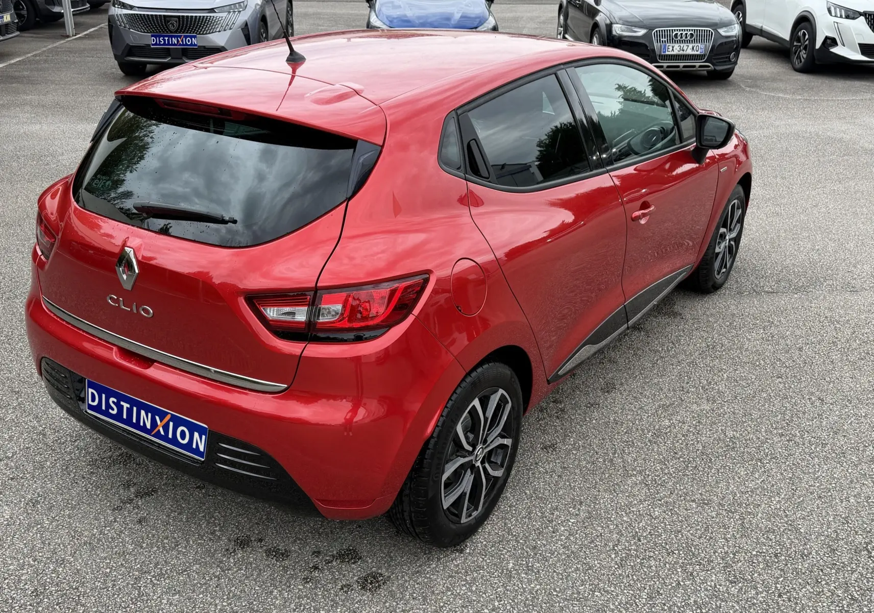 Vue 3/4 arrière droite d'une Renault Clio IV Limited TCe 90 rouge flamme avec vitres teintées et jantes alliage noires.