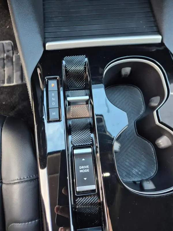 Vue rapprochée de la console centrale noire brillante de la Citroën C5 X 2024 avec sélecteur de boîte auto et commandes Drive Mode.